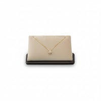 A chocolate and beige leatherette pendant stand with a cushioned surface displaying a single pendant necklace.