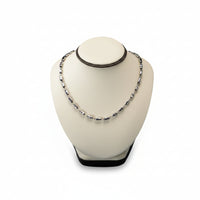 A mannequin head wearing a chocolate/beige leatherette neckform displaying a necklace.