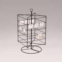 A bronze-colored metal rotating earring rack with multiple hooks to display earrings, placed against a neutral background.