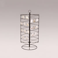 A black metal rotating earring rack with multiple hooks for displaying earrings, set against a neutral background.