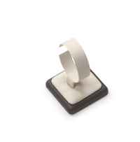 A chocolate and beige leatherette bangle/watch stand with a cushioned surface displaying a single bangle.