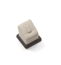 A chocolate and beige leatherette ring stand with a clip, designed to hold a ring securely in place.