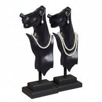 Black and white mannequin heads with jewelry on a white background