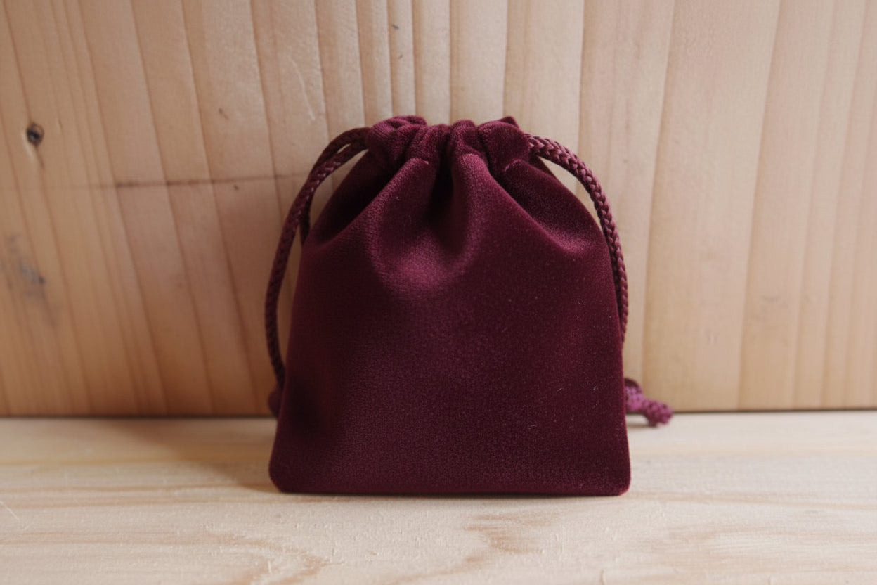Burgundy drawstring pouch on a wooden surface
