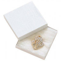 A white cotton filled jewelry box with a swirl pattern on the interior, containing a piece of jewelry, displayed open with a soft white exterior.