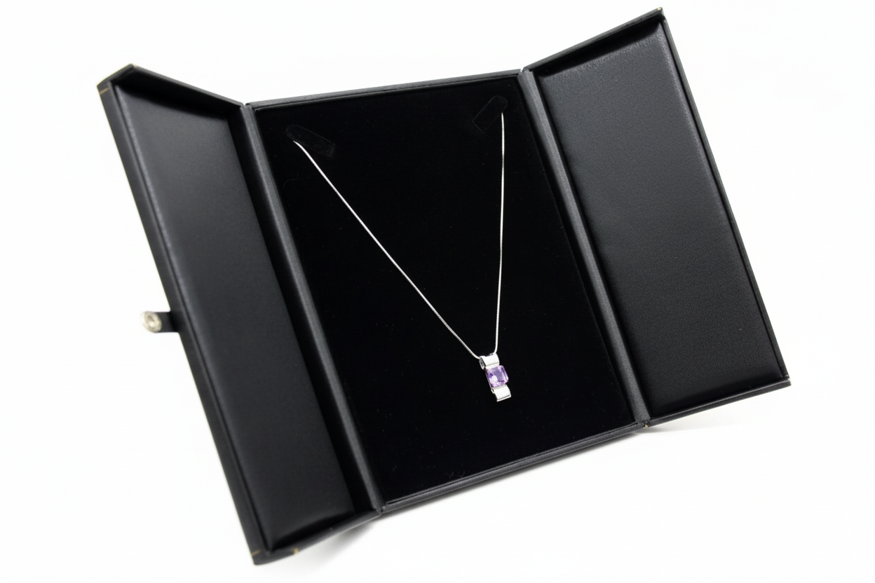 Necklace with a purple pendant in an open black jewelry box on a white background