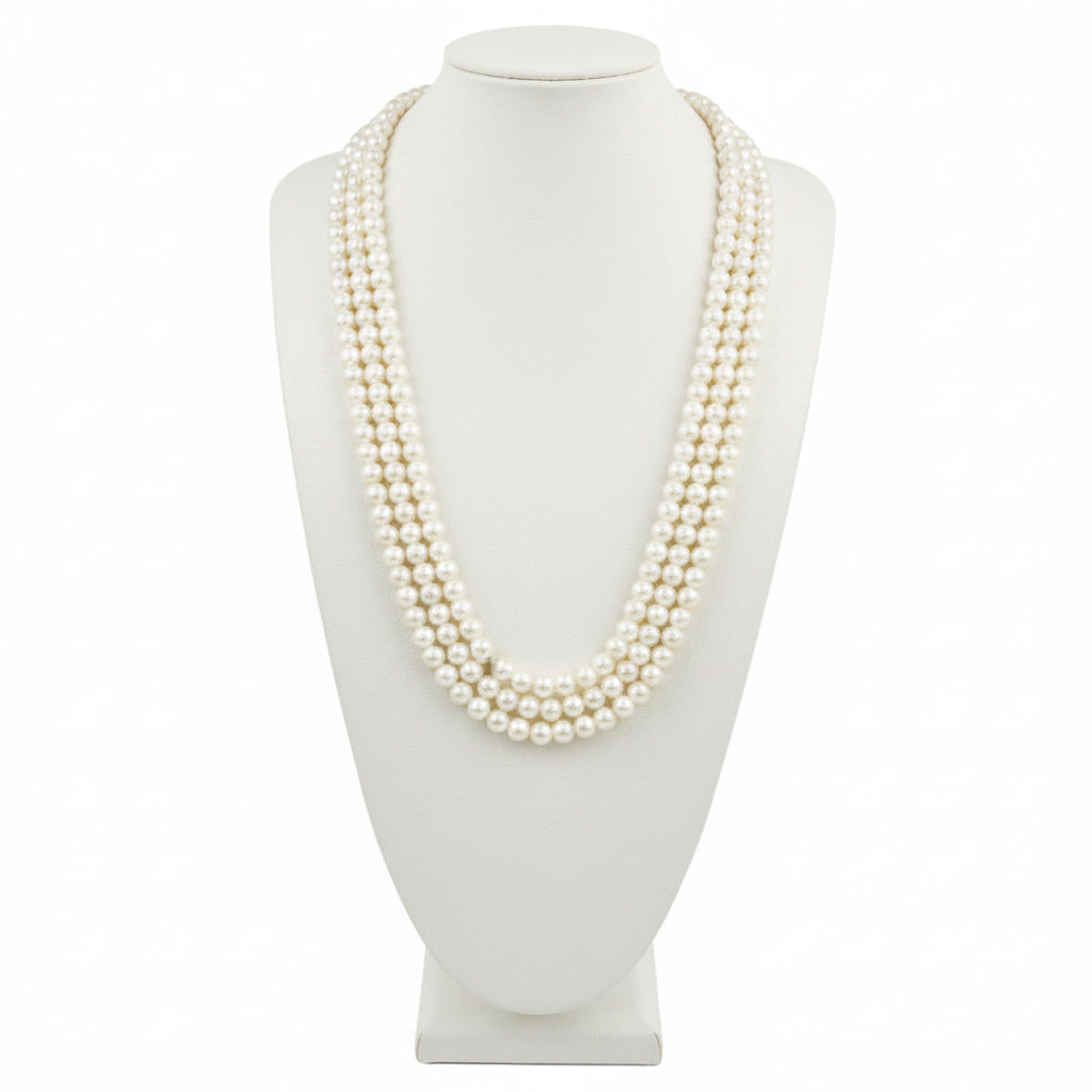 White pearl necklace on a black mannequin bust against a white background