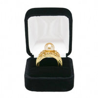 A metal ring box wrapped in plush velveteen fabric, displayed in a black setting.