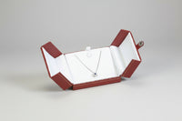 A leatherette double door pendant box opened to display a necklace, with a white interior and red exterior.