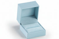 A light blue leatherette ring slit box is open, showing a light blue suede interior.